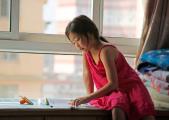 A girl doing her summer homework near by the window