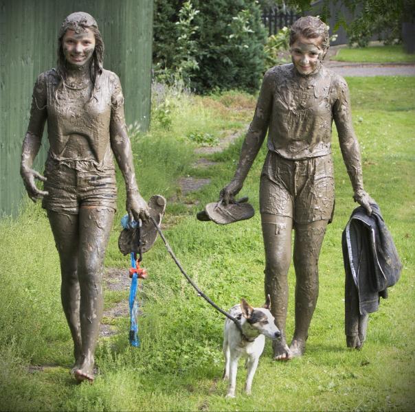 Mud swimming athletes walking home in Orford, Suffolk, England