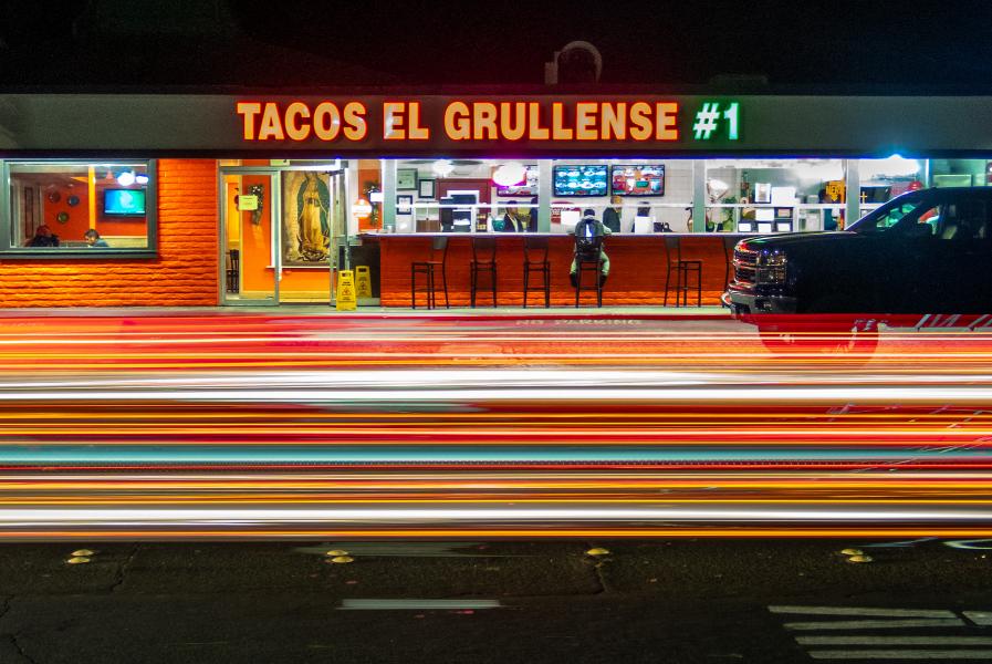 Cars in a hurry stream past a Redwood City taqueria