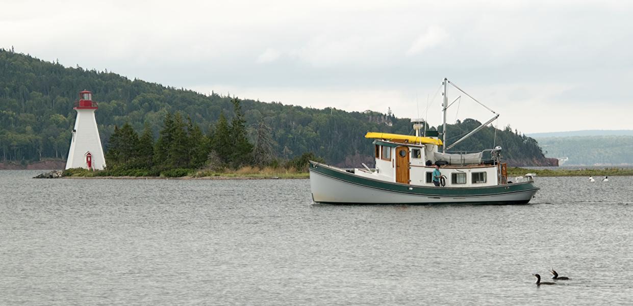 Fishing boat, cormorants and lighthouse in Nova Scotia, Canada.