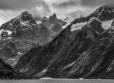 Mountains towering over a few icebergs floating in Greenland's Prince Christian Sound