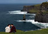 Couple takes selfie while sitting atop the Cliffs of Moher, Ireland