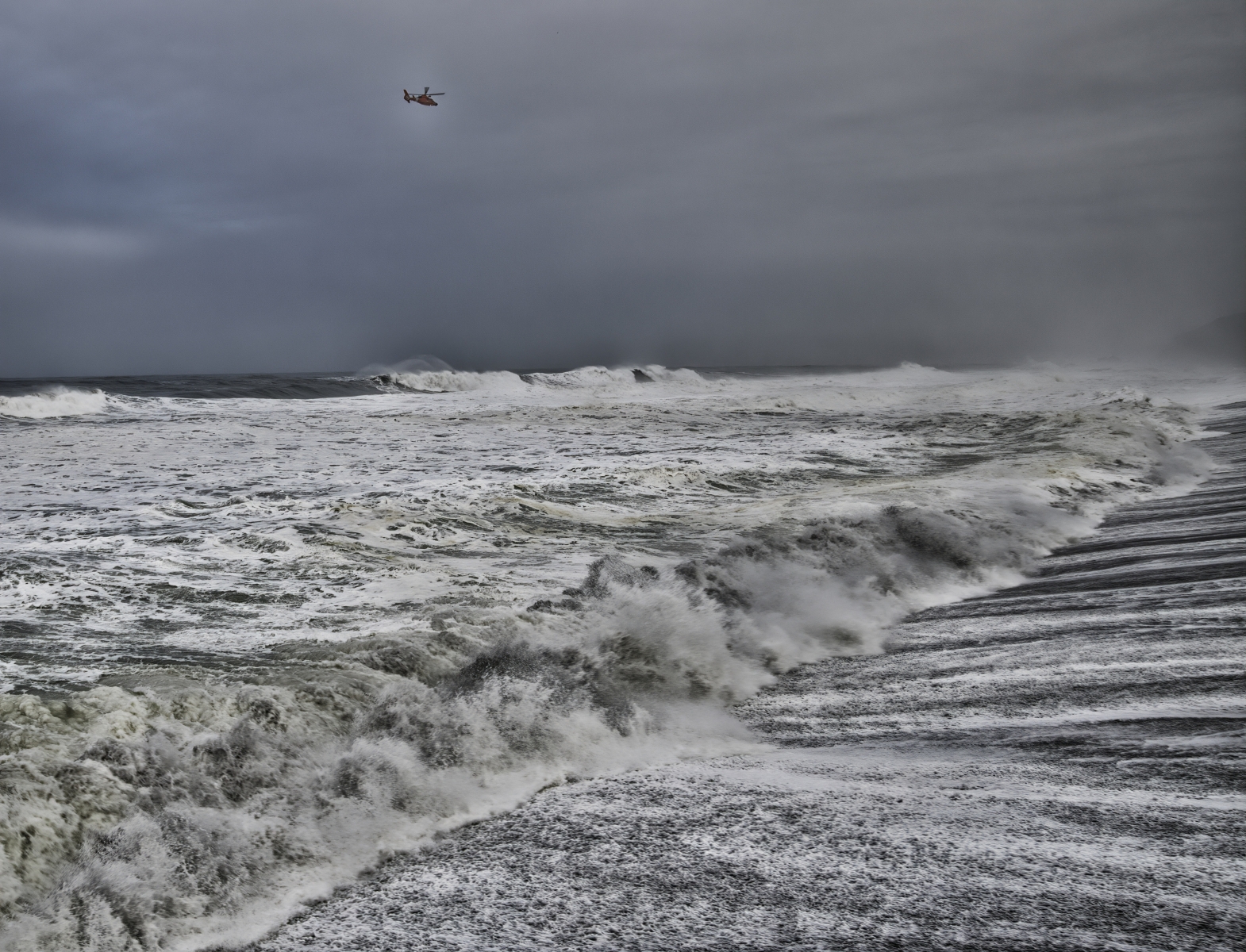 A coast guard helicopter searches the raging surf for the source of a red flare that was reported off the coast of Pacific, Ca, morning of January 18, 2019.
