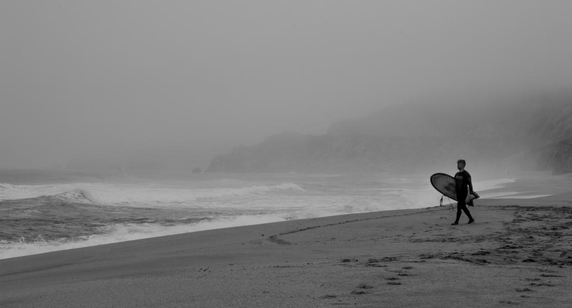 A determined surfer on a foggy morning